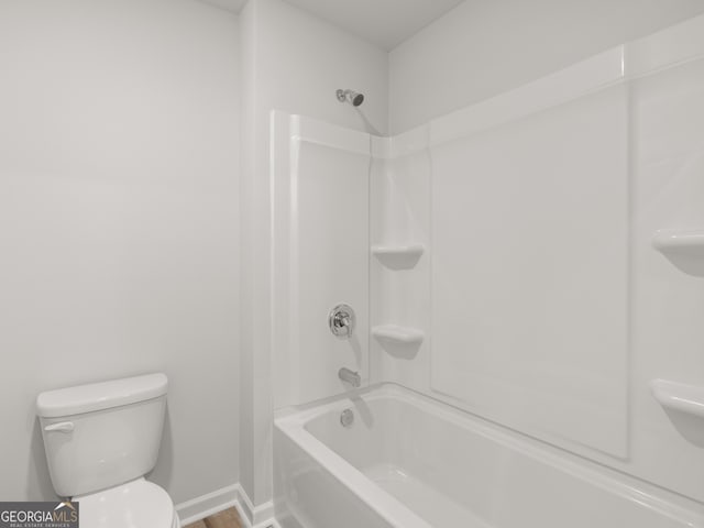 bathroom with toilet, baseboards, and shower / bathing tub combination