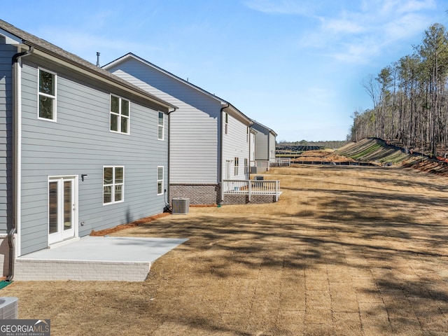 rear view of house featuring a patio, brick siding, and central AC