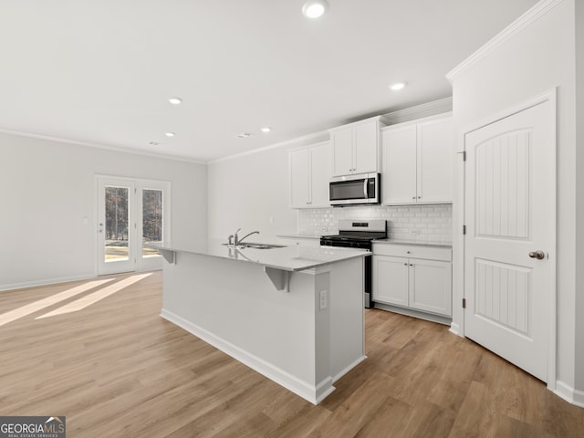 kitchen with crown molding, backsplash, appliances with stainless steel finishes, white cabinetry, and a sink