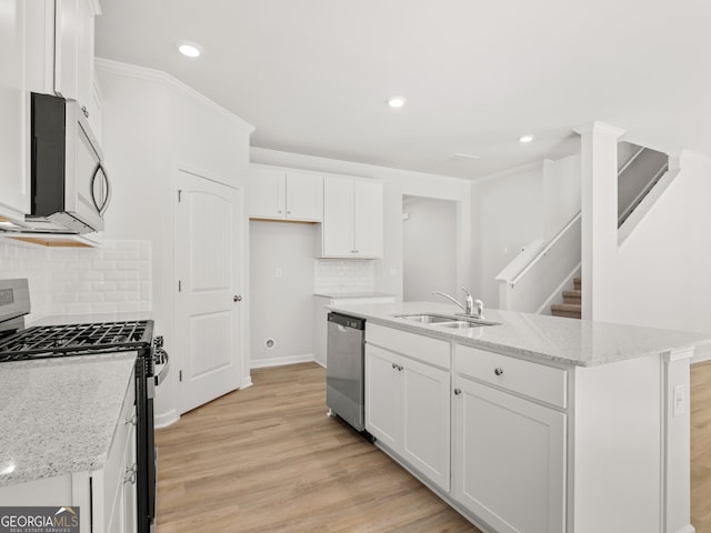 kitchen with light wood finished floors, appliances with stainless steel finishes, ornamental molding, white cabinetry, and a sink