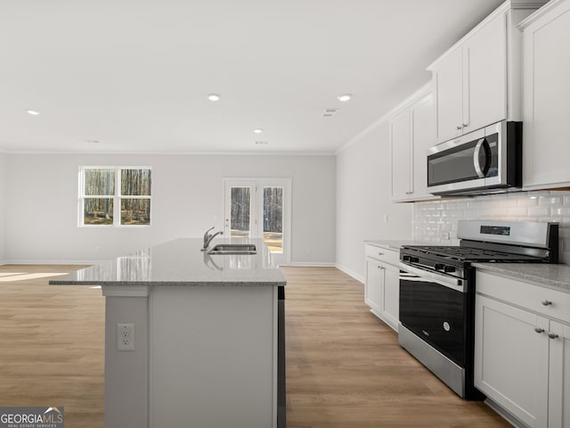 kitchen featuring stainless steel appliances, decorative backsplash, ornamental molding, a sink, and plenty of natural light