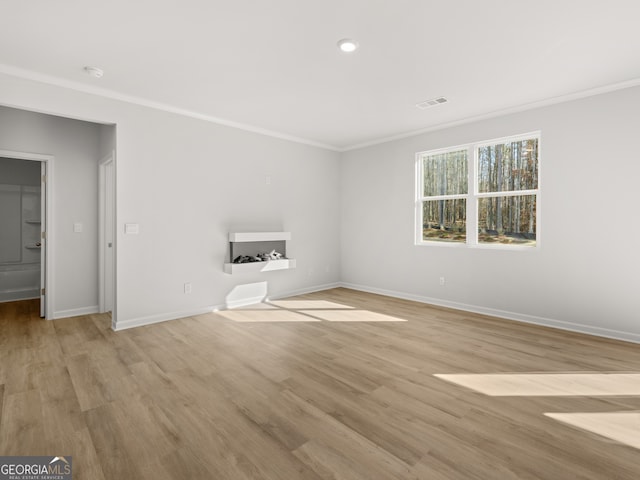 interior space with visible vents, ornamental molding, light wood-style flooring, and baseboards