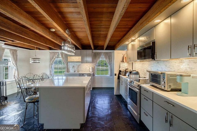 kitchen with beam ceiling, stainless steel appliances, stone tile flooring, light countertops, and gray cabinets