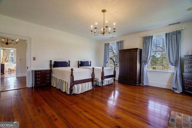 unfurnished bedroom featuring a chandelier, wood-type flooring, visible vents, and baseboards