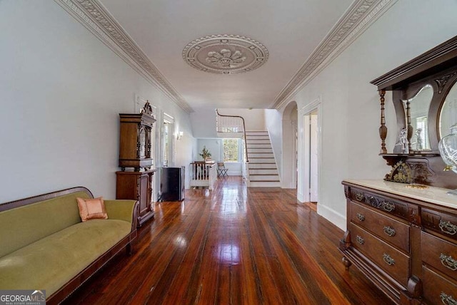 hall featuring baseboards, arched walkways, stairway, hardwood / wood-style floors, and crown molding