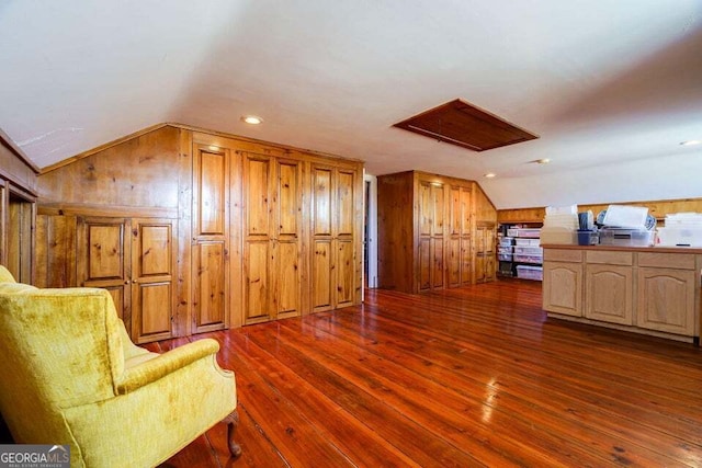 interior space with lofted ceiling, dark wood-style floors, and wooden walls