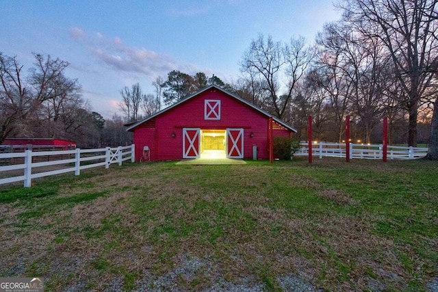 view of barn featuring a lawn and fence