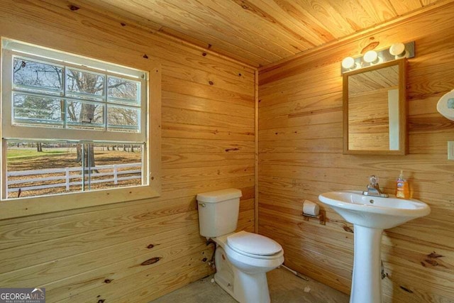 half bathroom with toilet, wood walls, and wood ceiling