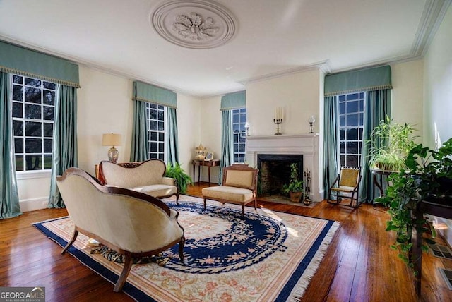 living area featuring a fireplace with flush hearth, ornamental molding, and hardwood / wood-style flooring