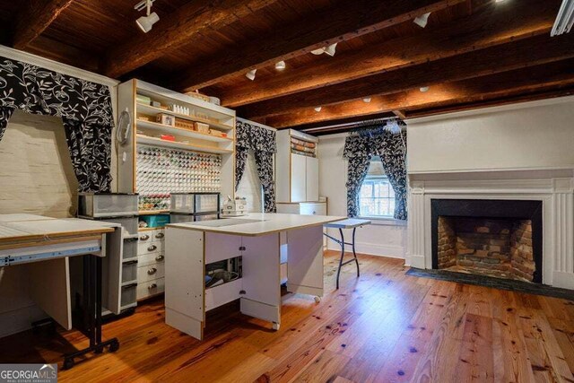 interior space with wood-type flooring, open shelves, beamed ceiling, and a fireplace with flush hearth