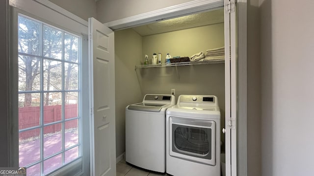 clothes washing area featuring laundry area, light tile patterned floors, and washing machine and clothes dryer