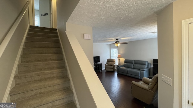 staircase with a textured ceiling, ceiling fan, hardwood / wood-style flooring, visible vents, and baseboards