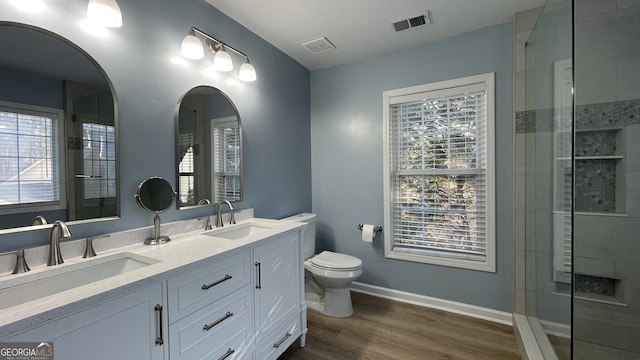 bathroom featuring toilet, wood finished floors, a sink, and visible vents