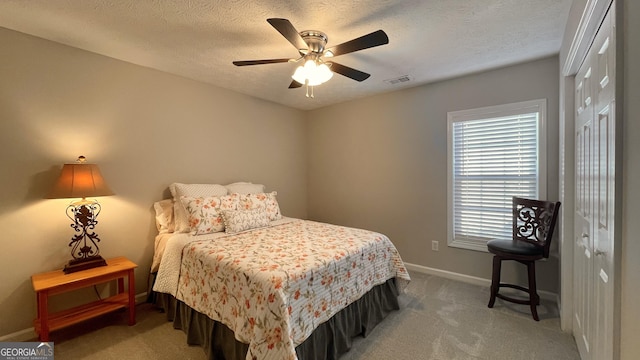 bedroom with baseboards, visible vents, light colored carpet, a textured ceiling, and a closet