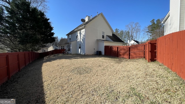 exterior space featuring a fenced backyard, a chimney, and a lawn