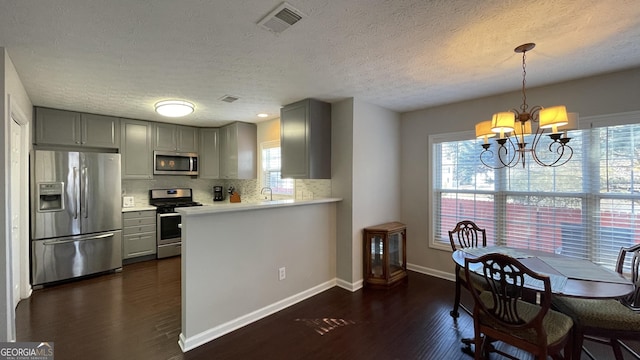 kitchen with dark wood finished floors, stainless steel appliances, tasteful backsplash, gray cabinets, and visible vents