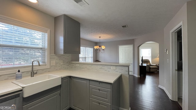 kitchen featuring tasteful backsplash, gray cabinets, visible vents, a sink, and a peninsula