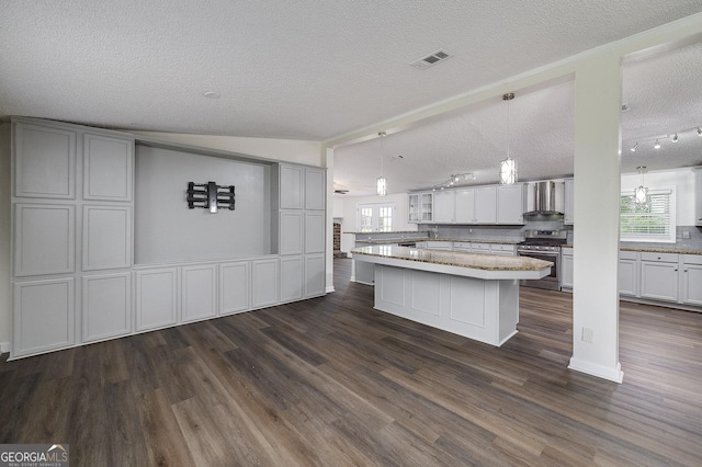 kitchen featuring stainless steel gas stove, wall chimney exhaust hood, plenty of natural light, and visible vents