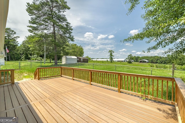 wooden terrace with an outbuilding, a fenced backyard, a lawn, and a storage unit