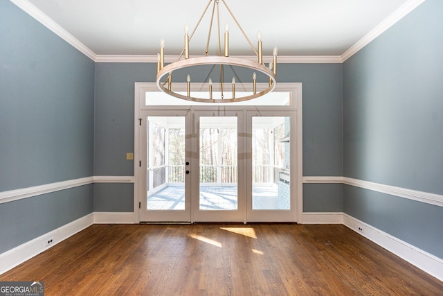 entryway with ornamental molding, a notable chandelier, baseboards, and wood finished floors