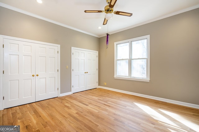 unfurnished bedroom featuring baseboards, ornamental molding, light wood-type flooring, two closets, and recessed lighting