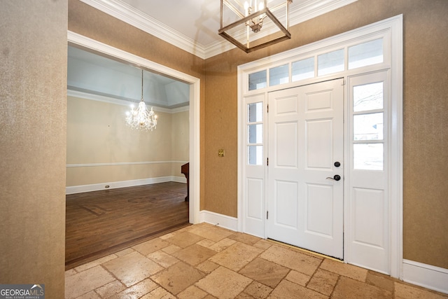 entryway with a chandelier, stone tile flooring, and ornamental molding