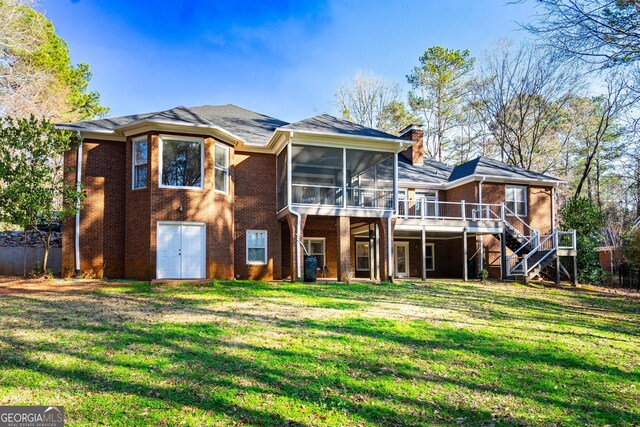 back of house with brick siding, a yard, a chimney, stairway, and a sunroom