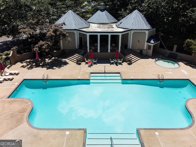 pool featuring an outbuilding, a patio, an exterior structure, and a hot tub