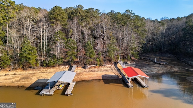 dock area with a water view, boat lift, and a wooded view