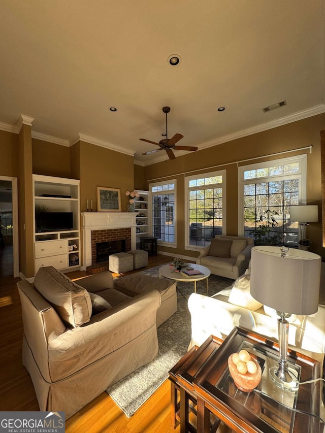 living room featuring a fireplace, recessed lighting, visible vents, ornamental molding, and wood finished floors