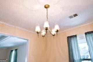 details with a chandelier, visible vents, and crown molding