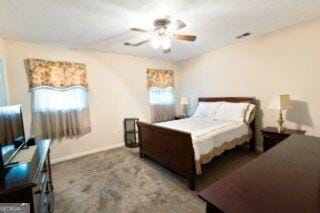 carpeted bedroom with multiple windows, a ceiling fan, and baseboards
