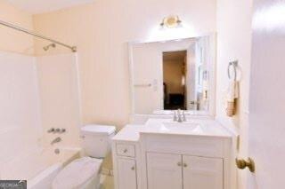 bathroom with tub / shower combination, vanity, and toilet