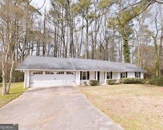 single story home with a garage, a front lawn, and aphalt driveway