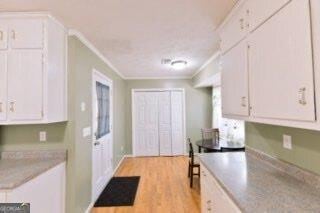 kitchen featuring ornamental molding, light countertops, white cabinetry, and light wood-style flooring