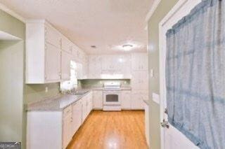 kitchen featuring light countertops, stove, white cabinetry, and light wood-style floors