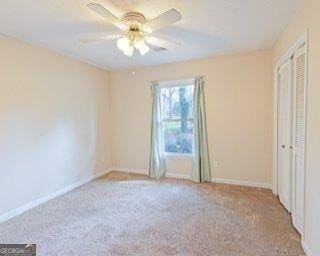 unfurnished bedroom featuring carpet floors, baseboards, and a ceiling fan