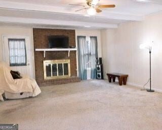 unfurnished living room with baseboards, a ceiling fan, beamed ceiling, carpet flooring, and a brick fireplace