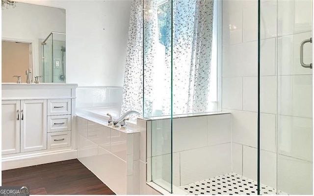 bathroom with a stall shower, a garden tub, wood finished floors, and vanity