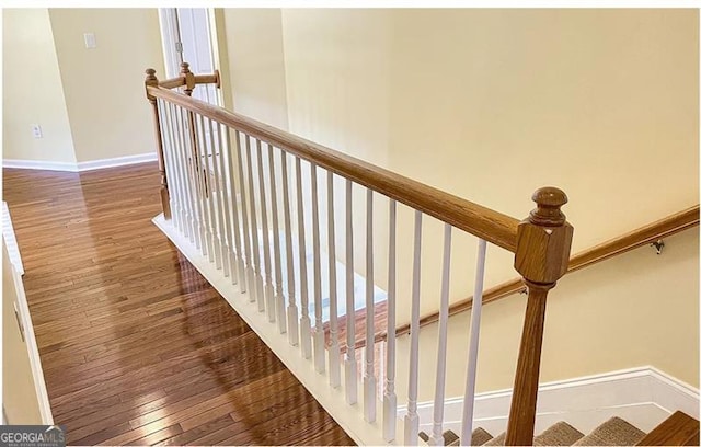 staircase with baseboards and wood finished floors