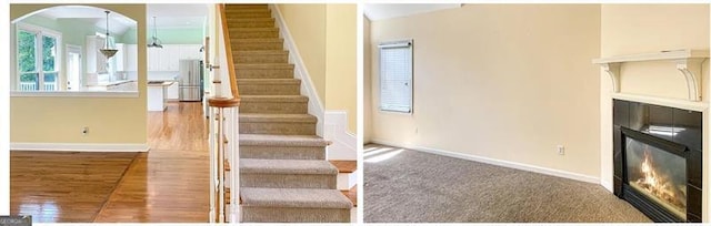 staircase featuring a glass covered fireplace, baseboards, and wood finished floors