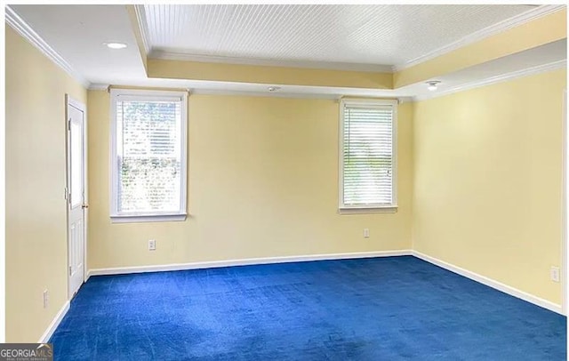 unfurnished room with dark carpet, a wealth of natural light, crown molding, and baseboards