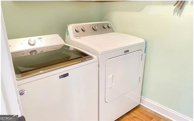 washroom with light wood-type flooring, laundry area, baseboards, and independent washer and dryer