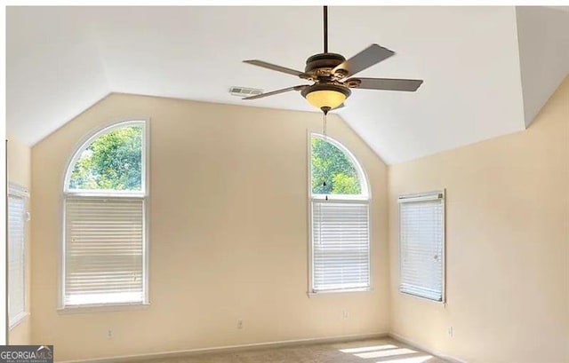 carpeted spare room featuring lofted ceiling, visible vents, and a healthy amount of sunlight