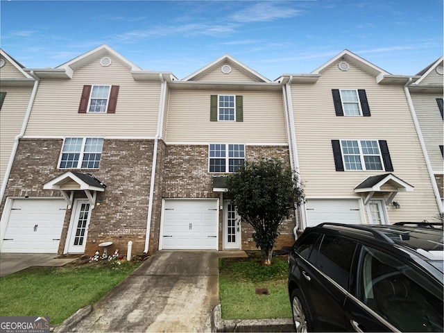 view of property featuring driveway, brick siding, and an attached garage