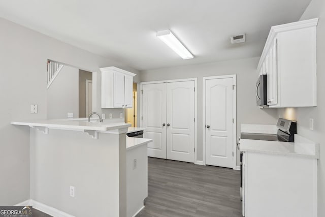 kitchen with stainless steel appliances, light countertops, visible vents, a peninsula, and a kitchen bar