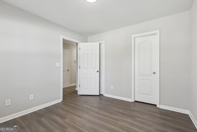 unfurnished bedroom with baseboards and dark wood finished floors