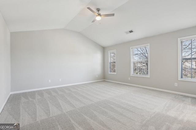 spare room with carpet floors, a wealth of natural light, visible vents, and lofted ceiling