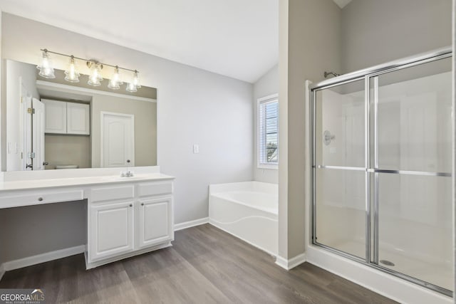 bathroom with vanity, a shower stall, wood finished floors, baseboards, and a bath