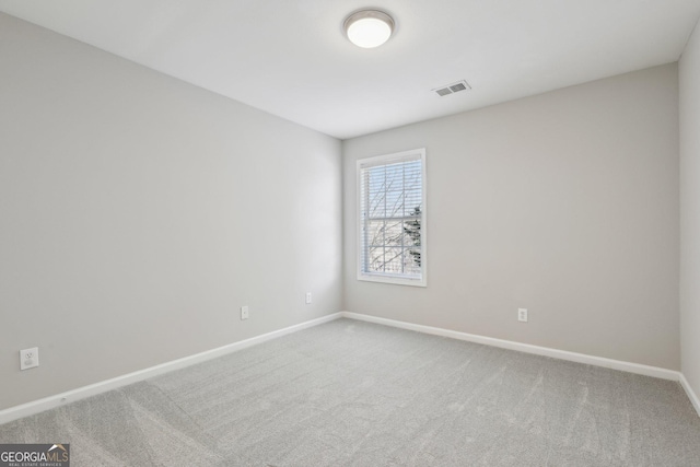 spare room featuring carpet flooring, visible vents, and baseboards